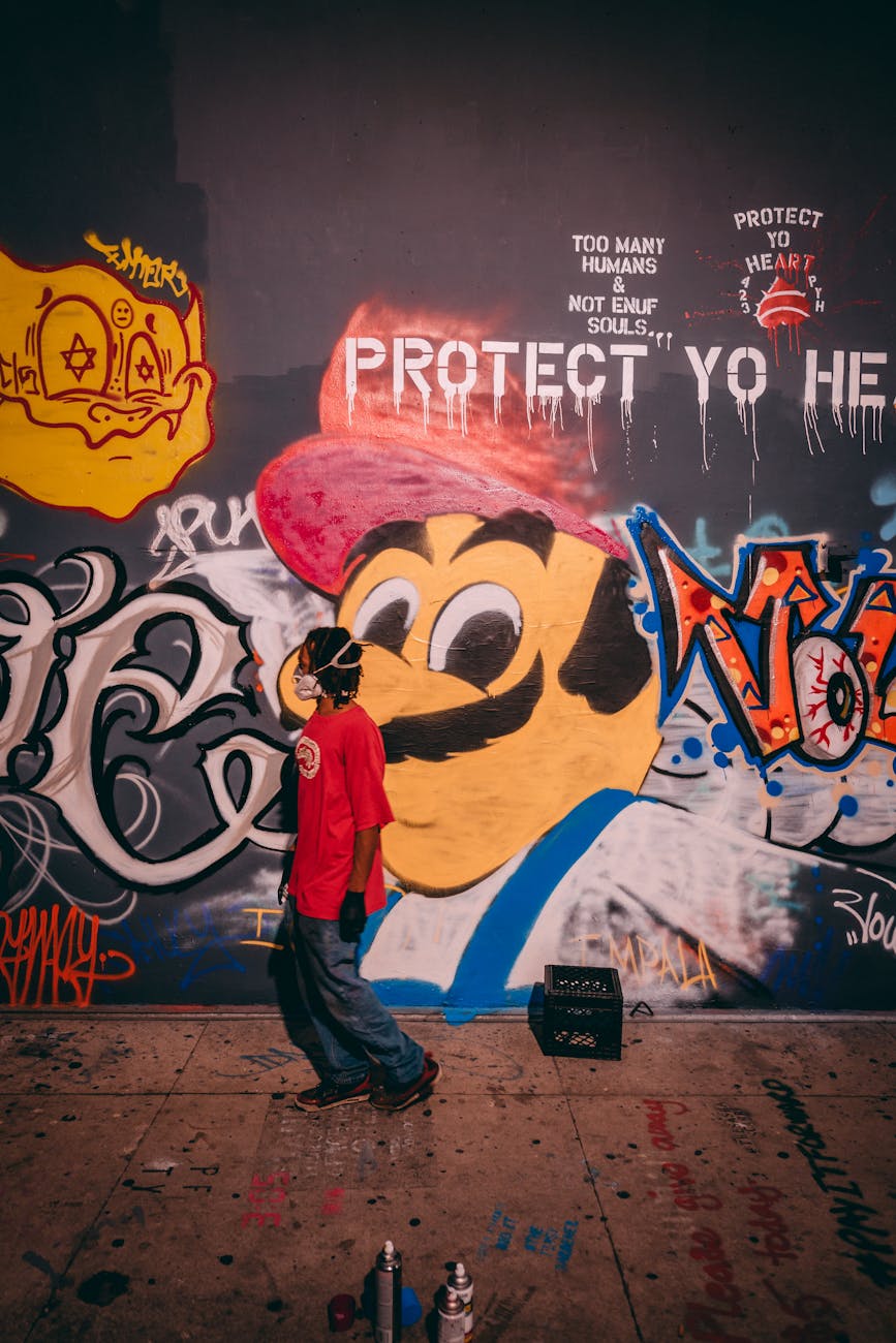 a man in a face mask standing beside a wall with graffiti